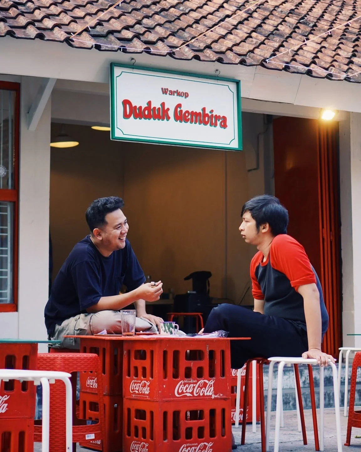 Teras Duduk Gembira dengan papan nama dan tempat duduk peti merah